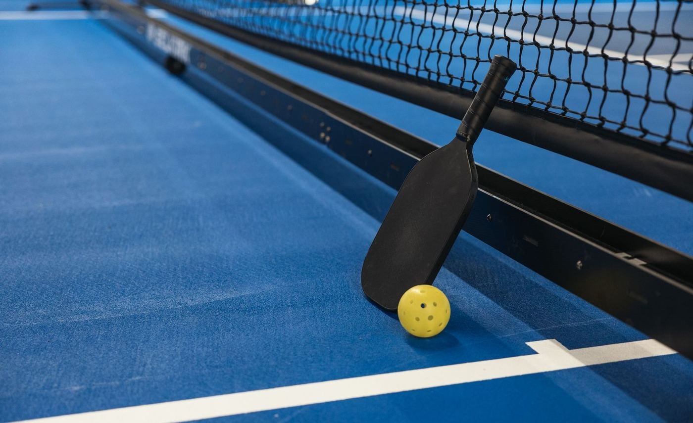 Pickleball paddle and ball at the net on an outdoor court